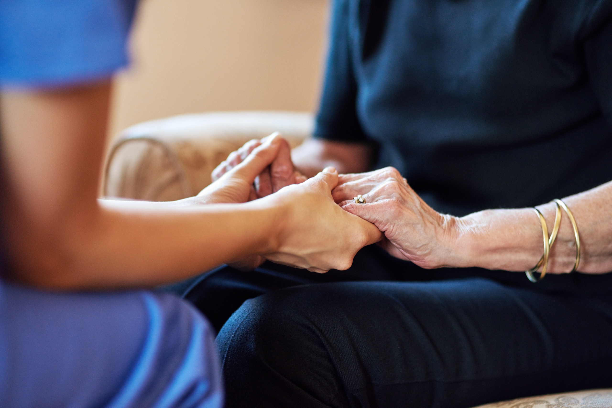 Eine Pflegekraft hält die Hände einer älteren Patientin